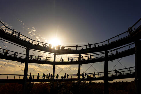 Deutschland, Bayern, Ebrach, Silhouetten von Menschen am Baumwipfelpfad bei Sonnenuntergang - NDF01000