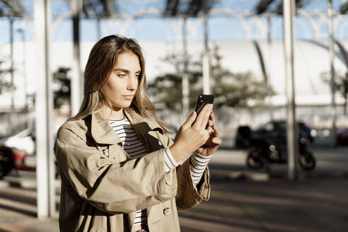 Junge blonde Frau, die ein Smartphone benutzt und ein Selfie macht - ERRF02006