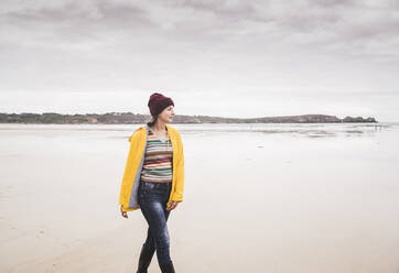 Junge Frau mit gelber Regenjacke am Strand, Bretagne, Frankreich - UUF19655