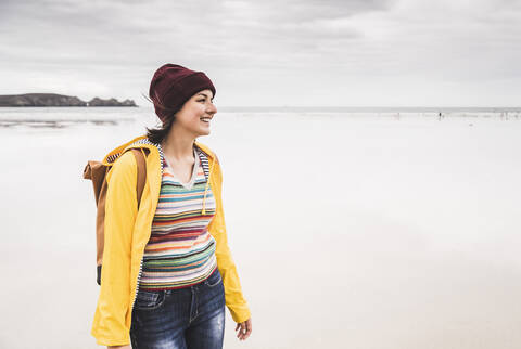 Junge Frau mit gelber Regenjacke am Strand, Bretagne, Frankreich, lizenzfreies Stockfoto