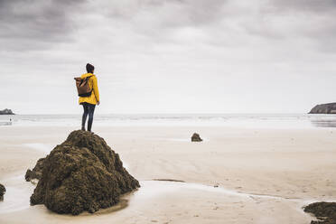 Young woman wearing yellow rain jacket at the beach, Bretagne, France - UUF19658