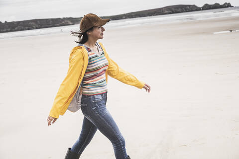 Young woman wearing yellow rain jacket at the beach, Bretagne, France stock photo