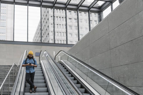 Mann auf Rolltreppe mit Smartphone, Berlin, Deutschland - AHSF01152