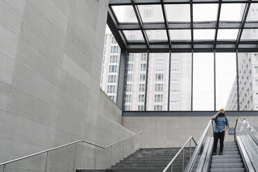 Mann telefoniert auf einer Rolltreppe, Berlin, Deutschland - AHSF01153