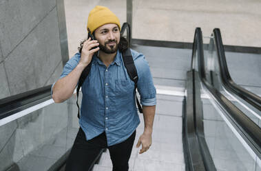 Porträt eines telefonierenden Mannes auf einer Rolltreppe - AHSF01156