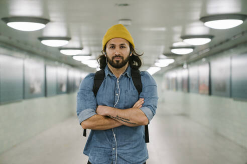 Portrait of bearded man with backpack and earphones in an underpass, Berlin, Germany - AHSF01172