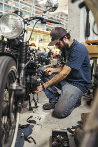 Mechaniker in einer Reparaturwerkstatt, der ein Motorrad repariert, lizenzfreies Stockfoto