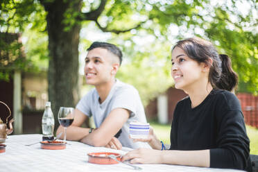 Smiling friends sitting at table in restaurant - MASF14324