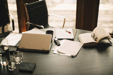 Hochformatige Ansicht von Dokumenten mit Buch und Laptop auf dem Tisch einer Anwaltskanzlei - MASF14415