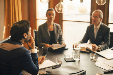 Male legal advisor discussing with colleagues in meeting at legal office - MASF14440