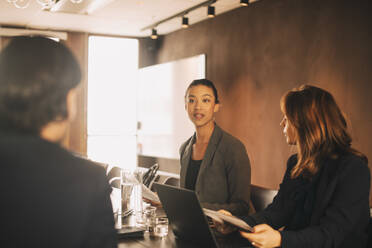 Mid adult lawyer sharing ideas with coworkers in meeting at board room - MASF14467