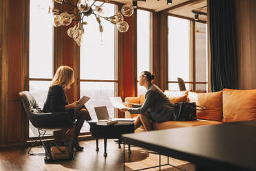 Legal colleagues discussing over documents in law office - MASF14474