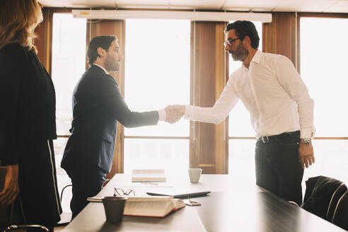 Businessman shaking hands with male lawyer after meeting in board room - MASF14503