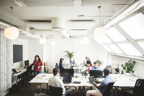 Blick von oben auf männliche und weibliche Fachleute, die an einem Schreibtisch in einem kreativen Büro arbeiten - MASF14547
