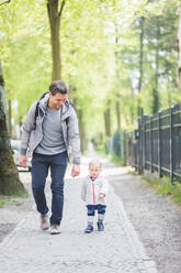 Lächelnder Vater in voller Länge mit Blick auf seinen Sohn auf dem Fußweg - MASF14574