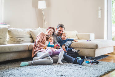 Portrait of happy parents sitting with children in living room at home - MASF14586