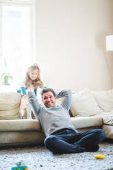 Cheerful father and daughter playing in living room at home - MASF14591