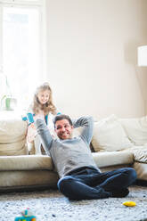 Fröhlicher Vater und Tochter spielen im Wohnzimmer zu Hause - MASF14591