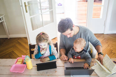Hohe Winkel Ansicht der lächelnden Vater mit niedlichen Sohn sitzt von Tochter mit digitalen Tablet am Tisch - MASF14604