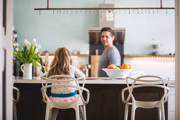Vater sieht seine Tochter beim Lernen an, während er in der Küche sitzt - MASF14624