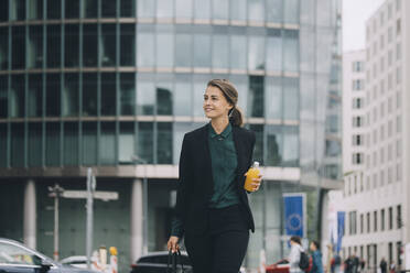 Confident businesswoman looking away while walking in city - MASF14634