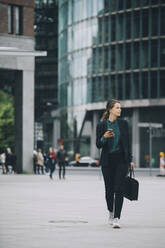Full length of confident businesswoman looking away while walking on street in city - MASF14647