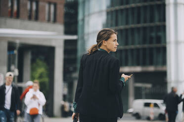 Rückansicht einer Geschäftsfrau, die beim Gehen auf einer Straße in der Stadt wegschaut - MASF14648