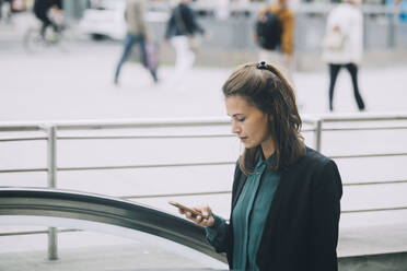 Selbstbewusste Geschäftsfrau mit Smartphone in der Stadt - MASF14652