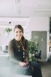 Portrait of smiling businesswoman sitting at table in creative office - MASF14668