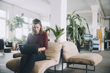 Selbstbewusste kreative Geschäftsfrau mit Laptop im Büro - MASF14676