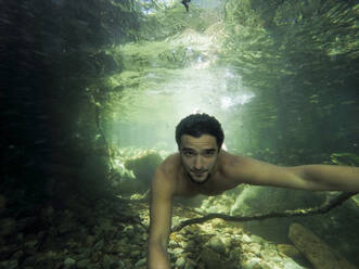 Selfie eines jungen Erwachsenen, der in einem sauberen Regenwaldfluss unter Wasser schwimmt - CAVF69073