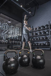 Man performing kettlebell overhead press at urban gym in Bangkok - CAVF69185