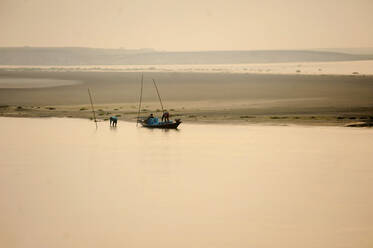 Men clearing the catch from their fishing nets at sunset in the fast flowing waters of the Brahmaputra River, Assam, India, Asia - RHPLF12656