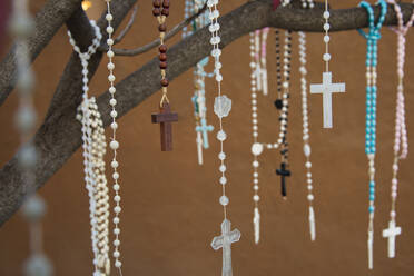 Von Gläubigen zurückgelassene Rosenkränze, die an einem Baum vor einer Kirche in Santa Fe, New Mexico, Vereinigte Staaten von Amerika, Nordamerika, hängen - RHPLF12722