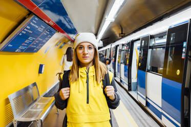 Porträt einer jungen Frau, die auf dem Bahnsteig einer U-Bahn-Station steht - JCMF00278