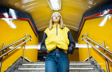 Junge Frau geht in einer U-Bahn-Station die Treppe hinunter - JCMF00279