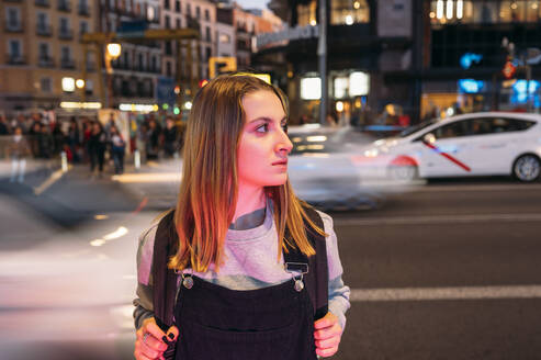 Junge Frau steht nachts in der Stadt auf der Straße - JCMF00284