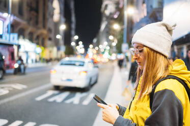 Junge Frau in der Stadt, die nachts ihr Smartphone benutzt - JCMF00288