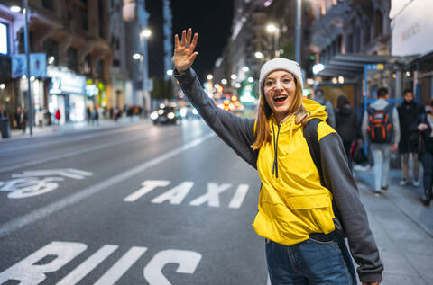 Young woman in the city hailing a taxi at night stock photo
