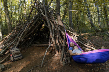 Vater und Tochter liegen zusammen in einer Hängematte im Wald - GEMF03295