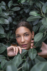 Portrait of young woman among green leaves - AFVF04207