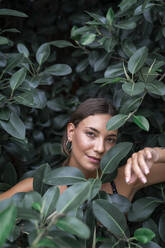 Porträt einer jungen Frau inmitten grüner Blätter - AFVF04208