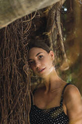 Porträt einer jungen Frau, die sich an einen Baumstamm lehnt - AFVF04212