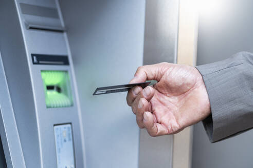 Nahaufnahme eines Geschäftsmannes, der an einem Geldautomaten Geld abhebt - DIGF08869