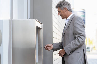 Mature businessman withdrawing money at an ATM - DIGF08870