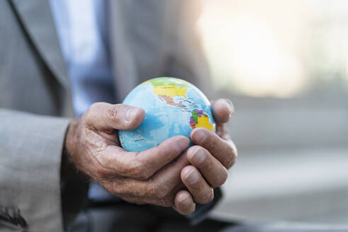 Close-up of hands of businessman holding globe - DIGF08881