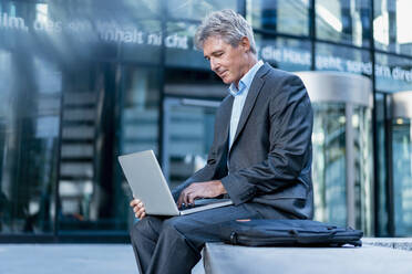 Mature businessman using laptop in the city - DIGF08888