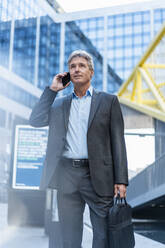 Mature businessman on the phone in the city - DIGF08901