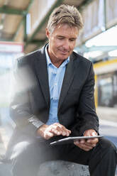 Älterer Geschäftsmann mit Tablet am Bahnsteig - DIGF08916