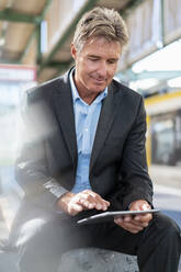 Mature businessman using tablet at station platform - DIGF08916